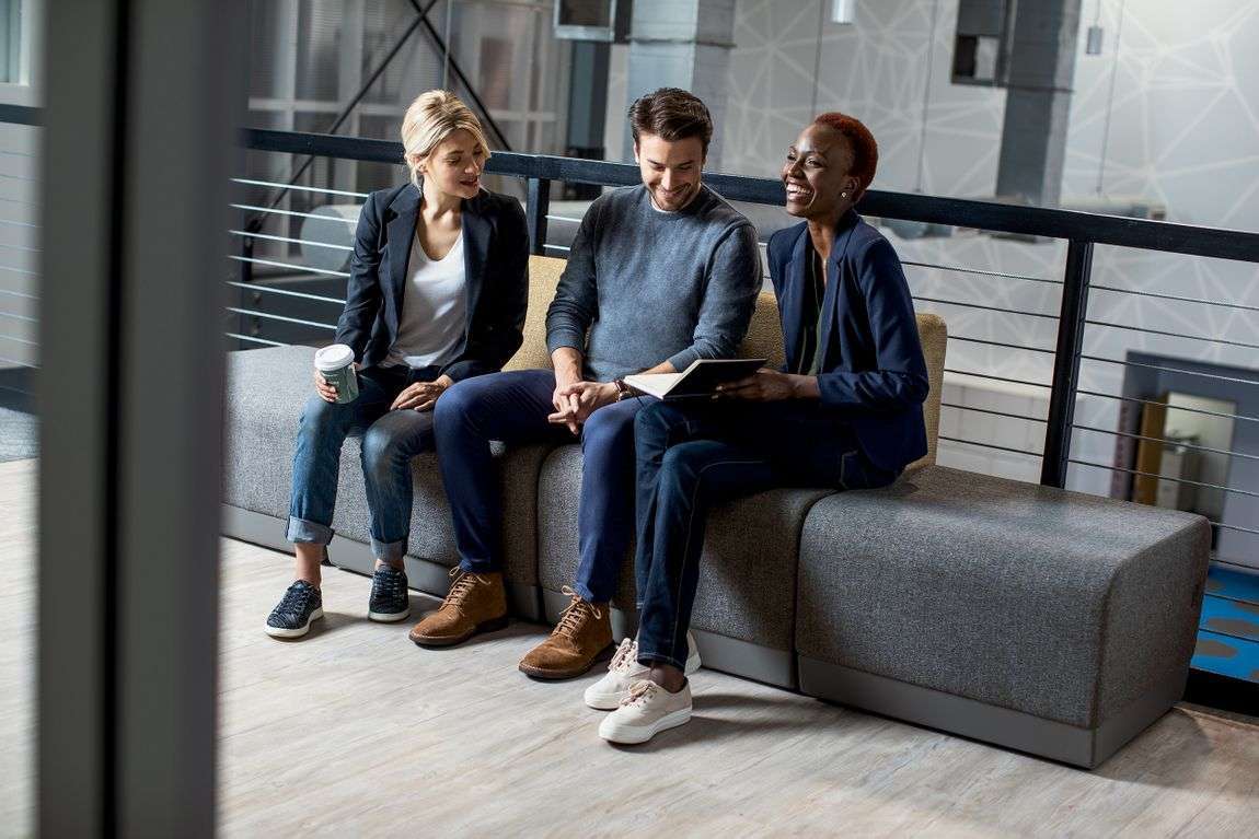 Three millennials sitting together talking at work